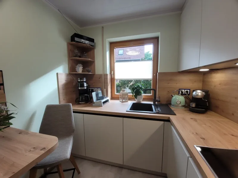 Detailansicht auf die Spüle unter dem Fenster und das hölzerne Eckregal.