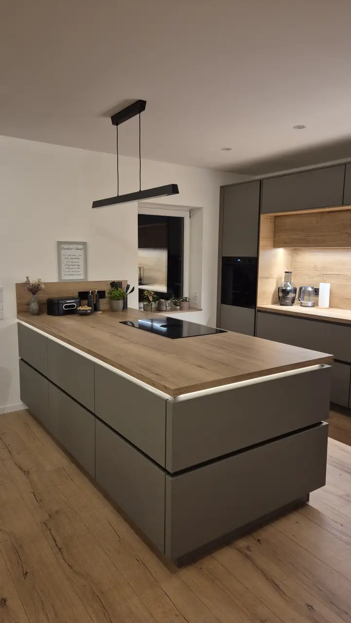 Detailansicht mit Fokus auf die Kücheninsel mit indirekter Beleuchtung und Kochfeld.