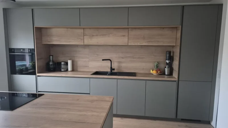 Detailansicht mit Blick auf die Küchenzeile. Im Fokus liegt die Spüle vor der Holzvertäfelung.