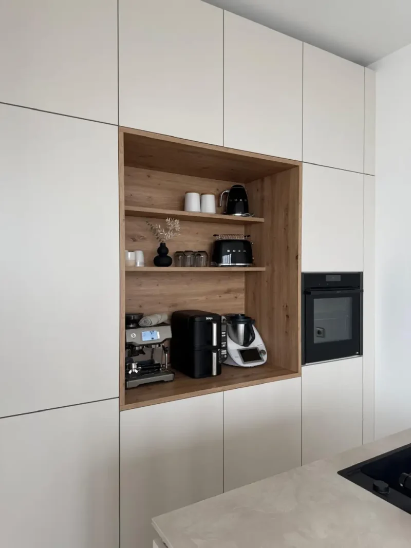 Detailansicht zur weißen Küche mit Fokus auf das integrierte Regal in Holzoptik