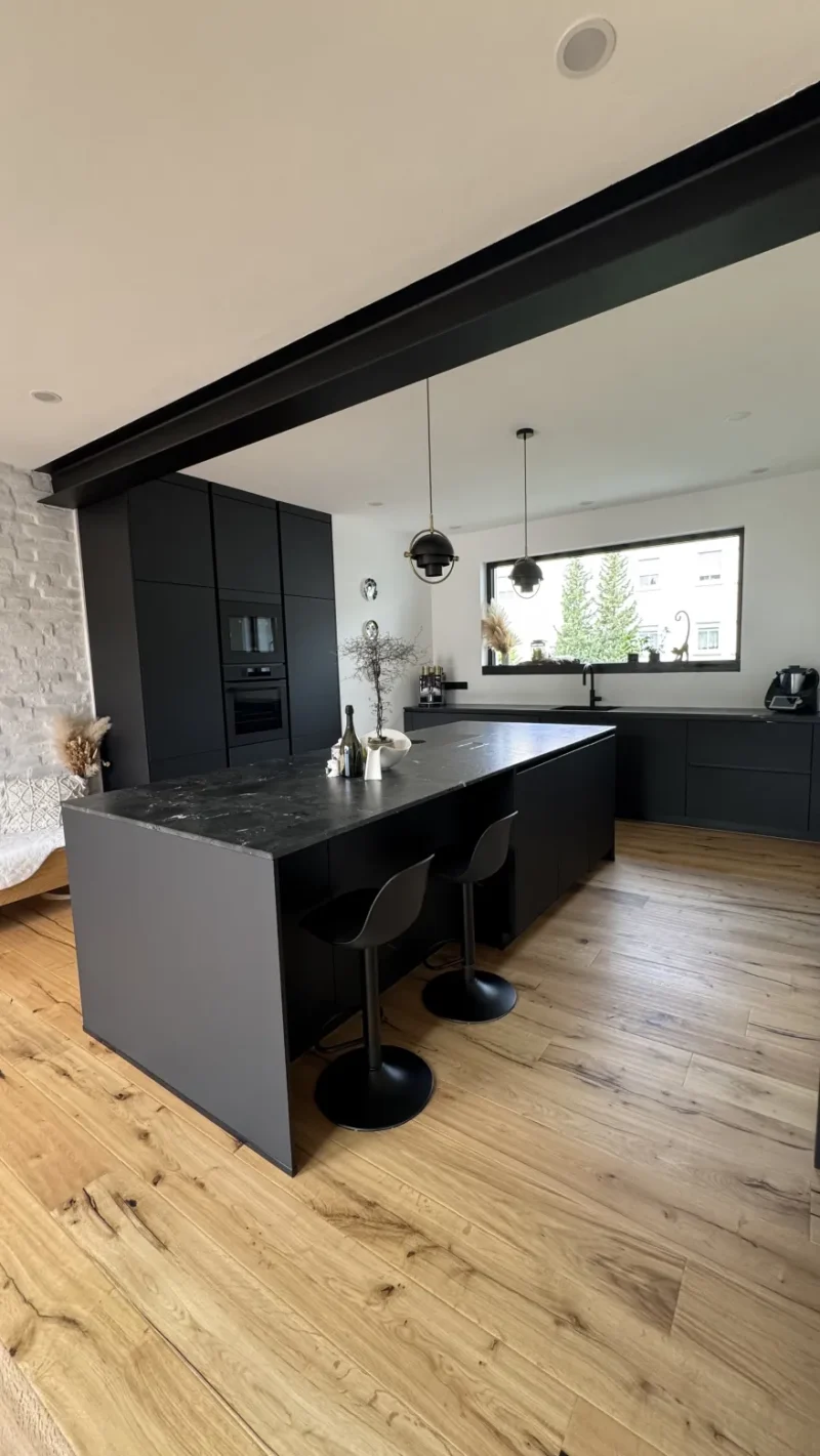 Blick auf die schwarze Kücheninsel mit Sitzgelegenheiten.