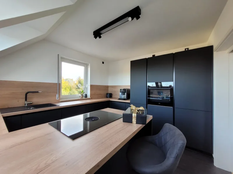 Detailansicht mit Blick auf die hölzerne Arbeitsplatte und das integrierte Kochfeld mit Muldenlüfter