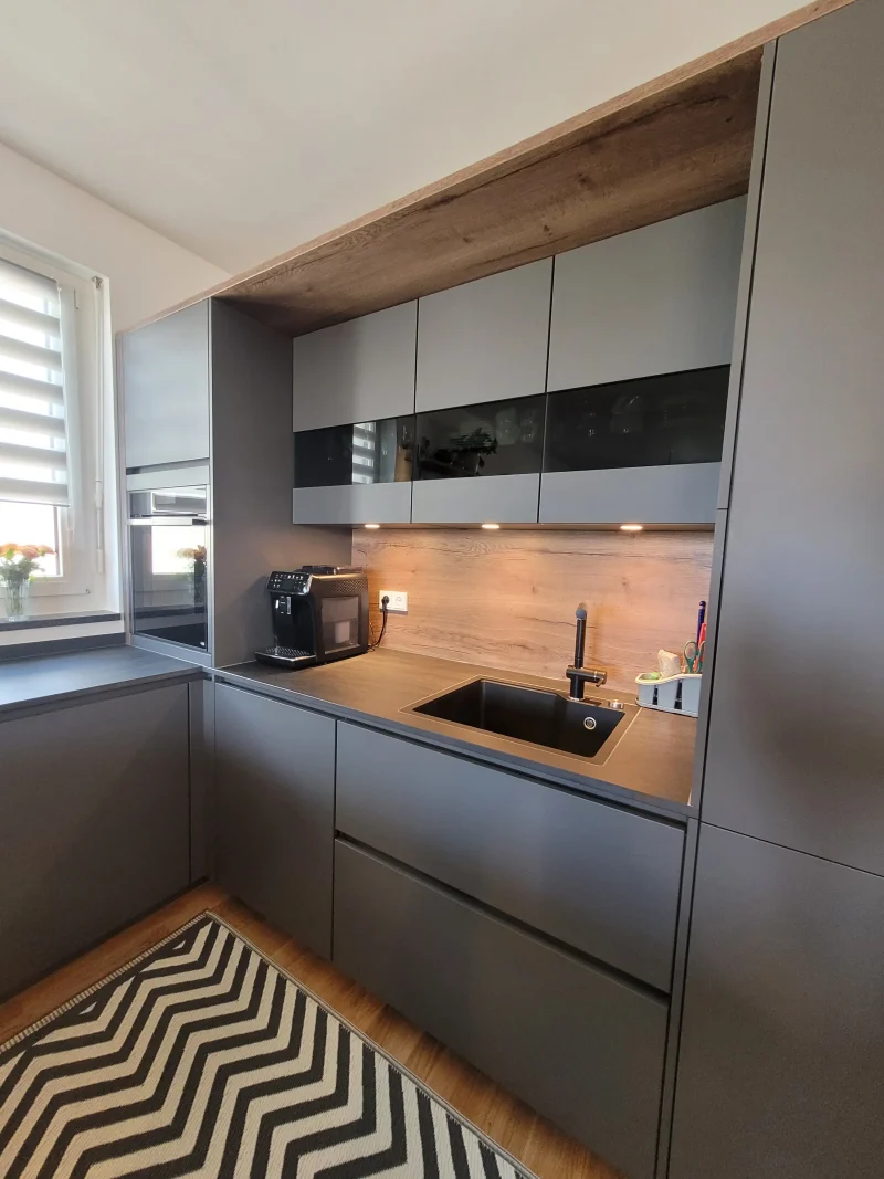 Detailansicht des Spülenbereiches mit Holzdekor an der Wand und indirekter Beleuchtung.