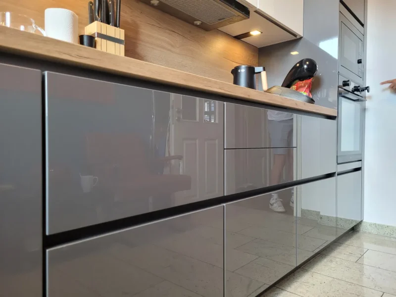 Detailansicht der grauen, unteren Küchenschränke. Grifflos und in Hochglanz