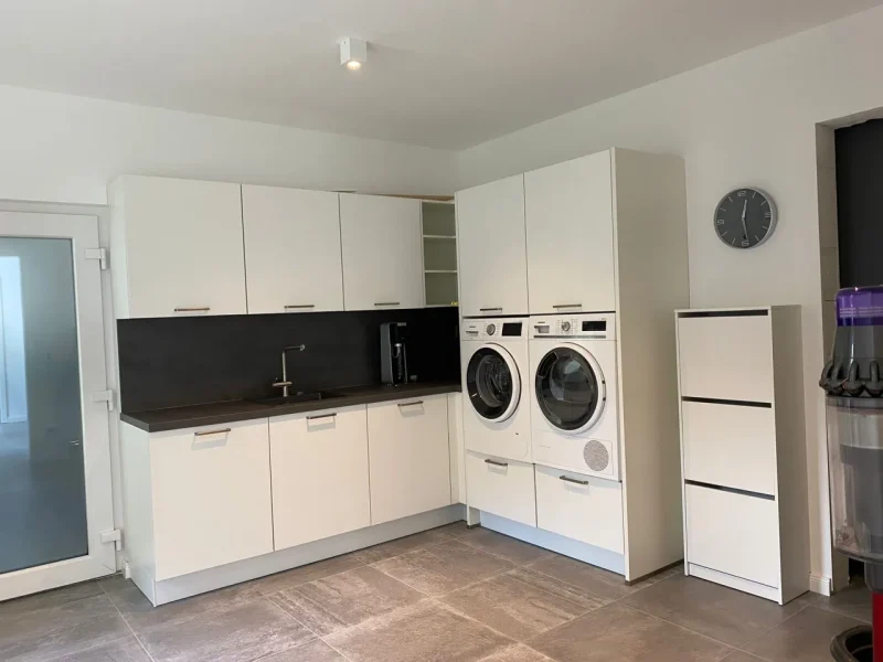 Ansicht des hell eingerichteten Hauswirtschaftsraumes mit Hochschränken in L Form