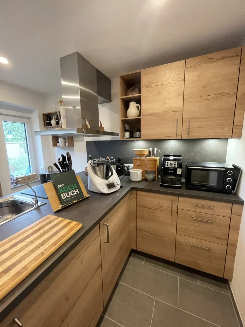 Blick auf die Inssenseite der Küchenzeilen mit Holzdekor und dunkler Arbeitsfläche