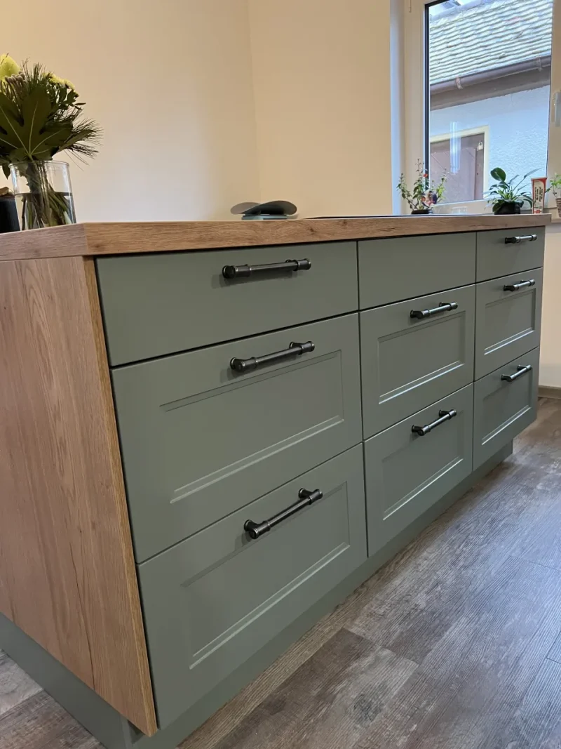 Blick auf die Schubläden des niedrigen Sideboards mit farbigen Fronten und hölzerner Fassung.