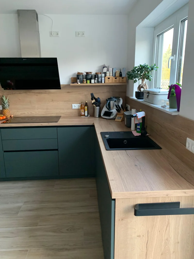 Detailansicht der langen Küchenzeile mit Spüle und Ausblick auf das Kochfeld mit Dunstabzug.