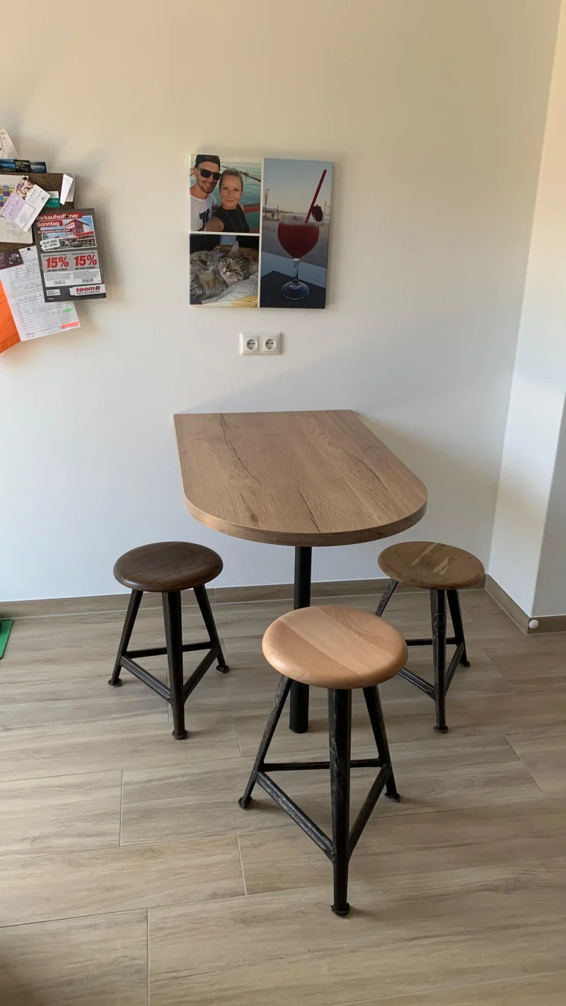 Detailansicht auf den kleinen, separaten Sitzbereich mit drei Hockern und Tisch.