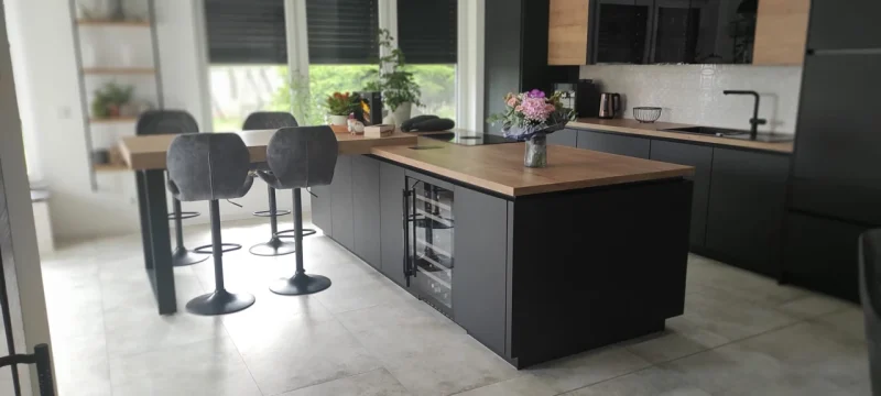 Seitliche Ansicht der Küche mit Fokus auf der Kochinsel und den Sitzgelegenheiten.